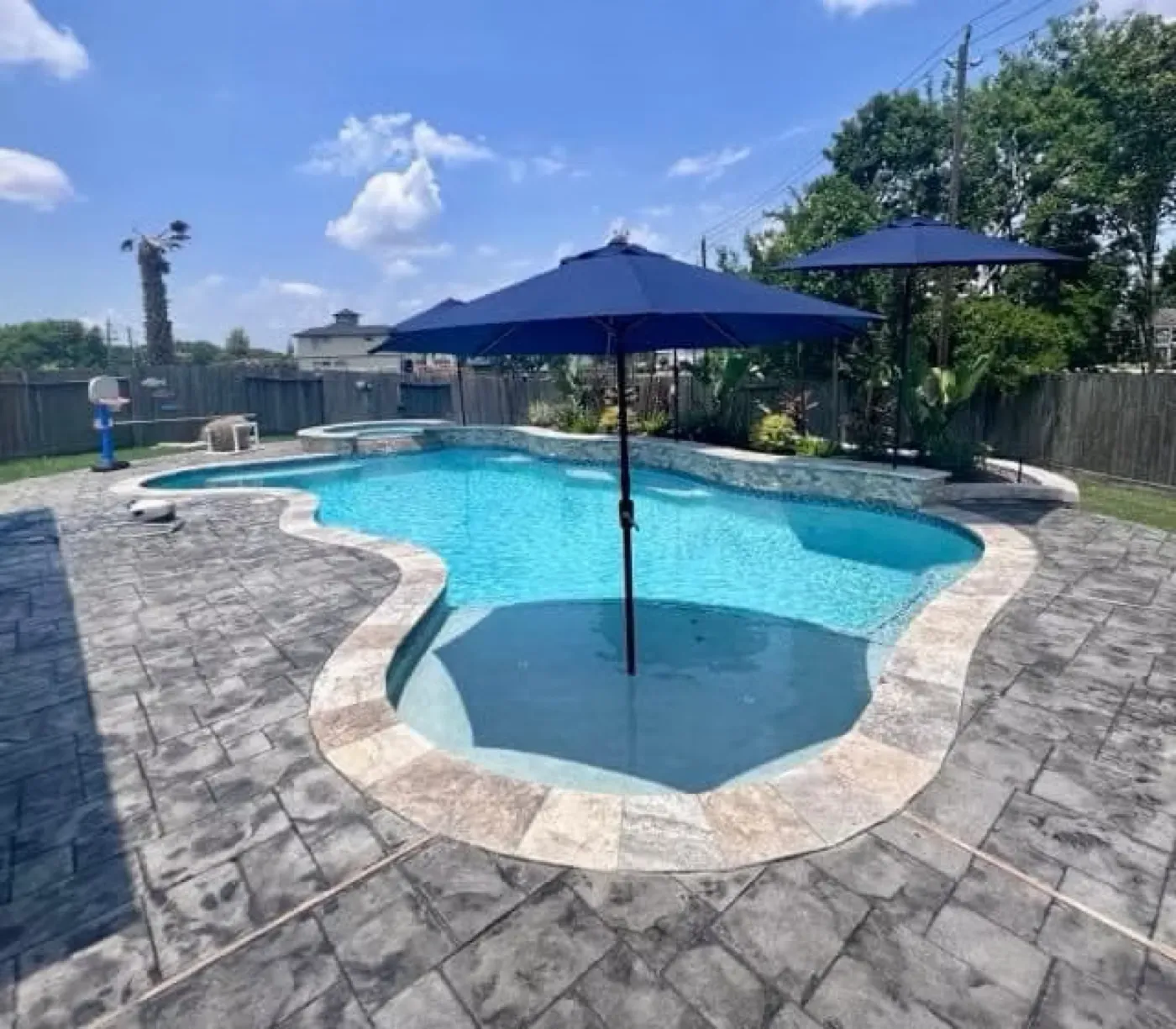 Freeform pool with blue umbrellas and spa