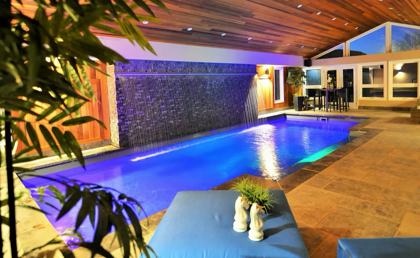 Pool illuminated at night with LED lighting and water wall feature