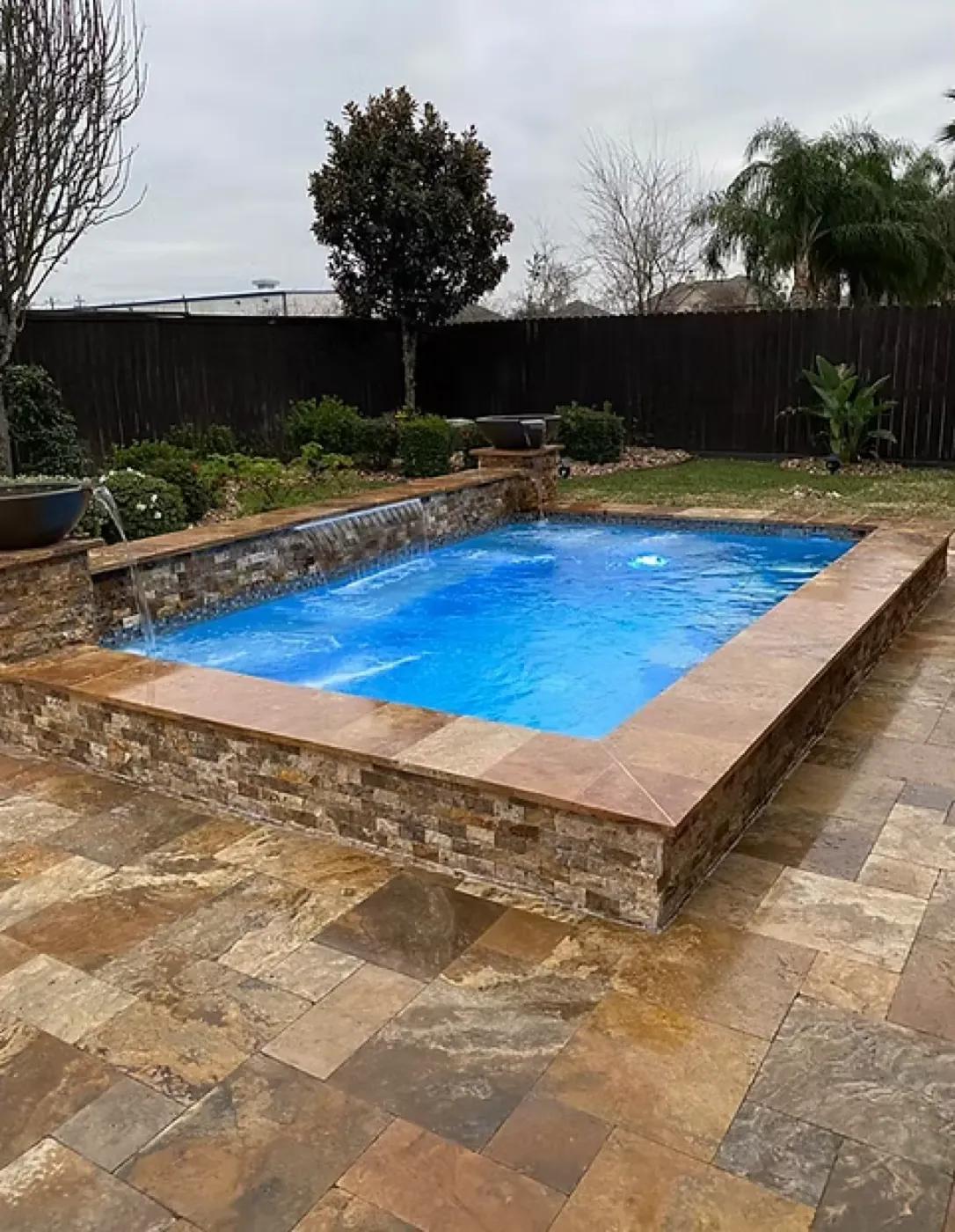 Raised stone-clad pool with cascading waterfall