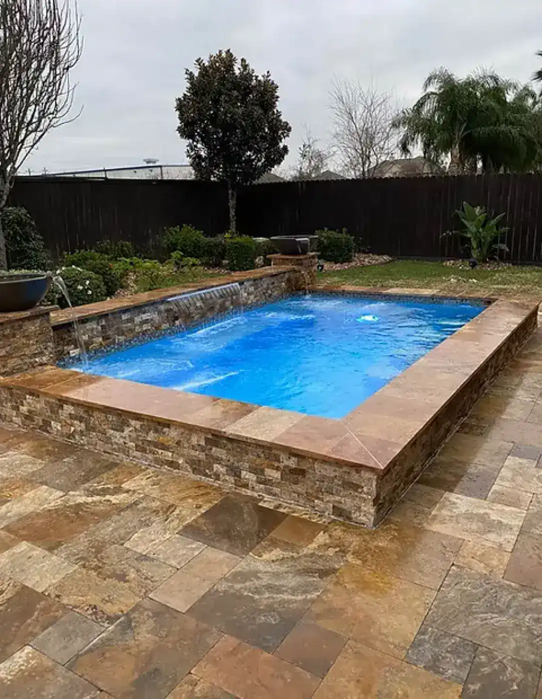 Raised stone-clad pool with waterfall